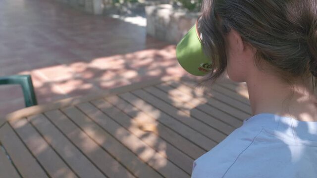 Woman enjoying a cup of coffee on a warm summer day. Plan of the girl drinking behind her left shoulder. 4k video quality