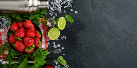 Food fresh ingredients for making lemonade, infused detox water or cocktail. Strawberries, lime, mint, basil, cane sugar, ice cubes and shaker on black stone or concrete background. Top view.