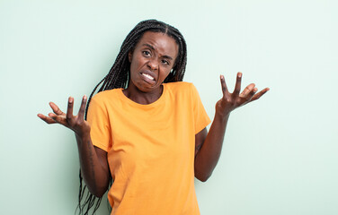 black pretty woman shrugging with a dumb, crazy, confused, puzzled expression, feeling annoyed and...
