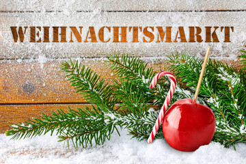 Weihnachtsmarkt und Liebesapfel mit Tannenzweigen auf Holz im Schnee