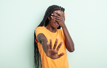 black pretty woman covering face with hand and putting other hand up front to stop camera, refusing...