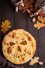 Halloween food. Homemade pumpkin pie or tart with a scary face for Halloween on a wooden table. Copy space. Halloween food concept.