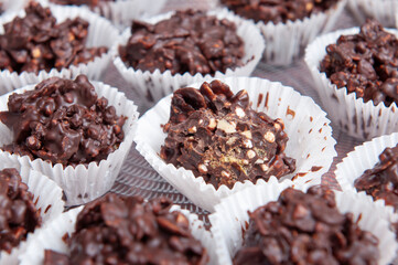 Chocolate candies with nuts, in a muffin white paper, on transparent round plate