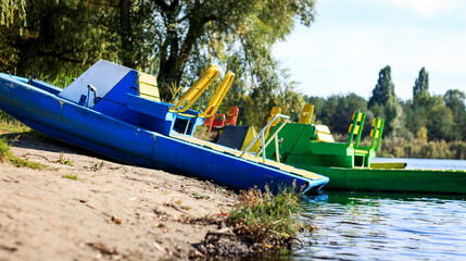 Metal catamaran blue close-up against the background of the forest and the sandy bank of the river...