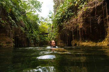 Woman swimming and floating along a beautiful tropical jungle river. Experiencing the natural beauty of Mexico. 