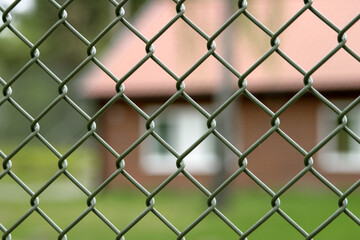 A green fence in focus with a red building in the background. Taken at a youth detention center in...