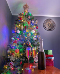 New years eve decoration with christmas tree and clock on the wall as a background and champagne in foreground.