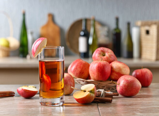 Glass of apple juice and ripe pink apples on a kitchen table