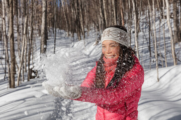 Winter fun Asian girl throwing cold snow in the air playing in forest. Winter season lifestyle