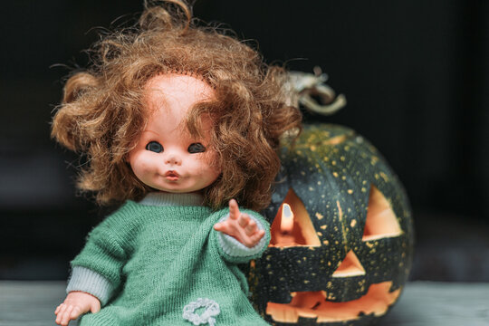 Close-up of carved pumpkin with old, vintage doll. Halloween decoration concept