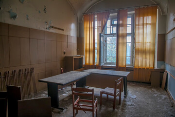 An old room in an abandoned hospital. Big window. Light passing through the window. Shabby walls. The interior of an abandoned building.