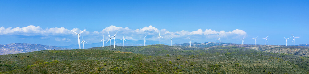 Oreites wind farm in Cyprus, wide panorama, landscape with green hills and blue sky
