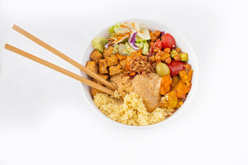 Big tasty vegan bowl with couscous, fried tofu, chickpeas, vegetables and peanut sauce with food sticks. Isolated on white, topview.