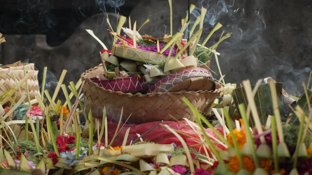 Baskets filled with flowers for Hindu religious offerings with burning sticks of incense at temple in Bali. Practices and beliefs of Hinduism. Traditional balinese offerings to gods. Tirta Empul Bali.