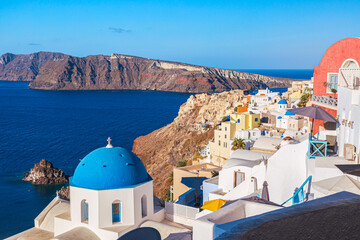 Oia village with famous white houses and blue churches on Santorini island, Aegean sea, Greece.