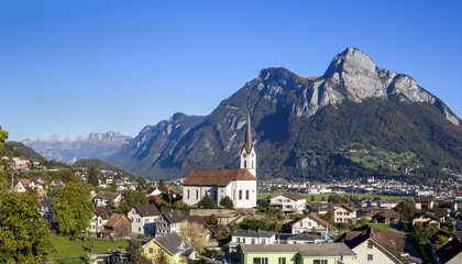 Fototapeta na wymiar Parish Church of St. Anthony at the st. Gallen town Wangs with Sargans, Mont Gonzen and the Churfirst mountain range at the background. The town is the starting point for Pizol trekking trails.
