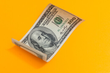 Single Hundred Dollar Bill Curled on yellow