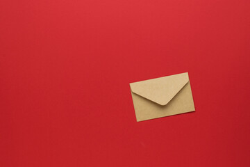 A closed paper postal envelope on a bright red background. Flat lay.
