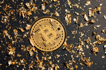 Bitcoin with pieces of golden leaves and dust on black background. Creative cryptocurrency or...