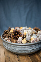 Weihnachten Dekoration – Metallschale mit verschiedenen Zapfen auf hölzernen Hintergrund 