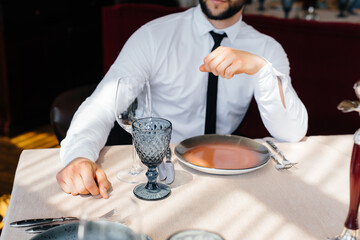 A young bearded male businessman is sitting at a table in a fine restaurant and waiting for his order. Customer service in the catering.