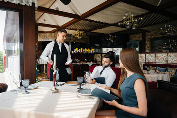 A stylish waiter serves a young couple who came on a date in a gourmet restaurant. Customer service...