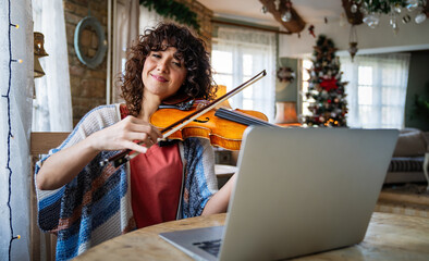 Woman music teacher teaching how to play a song the violin online during a video call