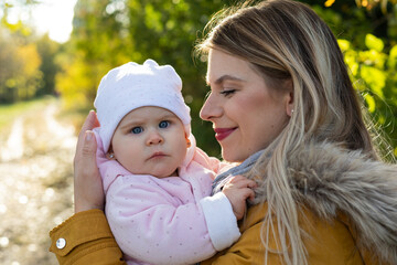 Happy beautiful mother spending time with her little baby girl in nature.