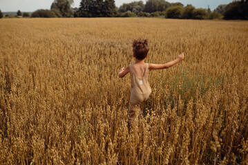 Chłopiec biegający w pszenicy w letnie, przedburzowe popołudnie w Polsce. 
