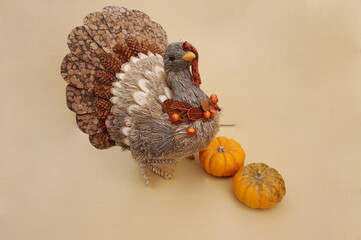 Turkey Figure Crafted from Natural Plant Material and Two Small Pumpkins on Golden Background