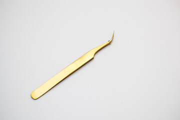 tools for eyelash extensions and eyebrow design. cosmetic tweezers in gold color on a white background