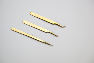 tools for eyelash extensions and eyebrow design. cosmetic tweezers in gold color on a white background