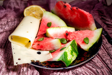 slices of watermelon and cheese sprinkled with fresh mint leaves on a white plate