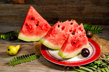 Sliced watermelon among dogwood berries on wooden table