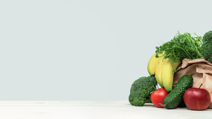 Fresh green vegetables in a basket on a wooden table. Banner with copy space. Green vegetarian diet or cuisine. Broccoli cabbage and celery. Grocery delivery or shopping online. Green diet