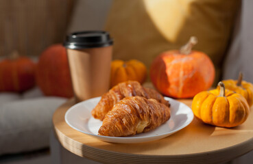 Freshly baked croissants and coffee with autumn pumpkins decor at a cafe 