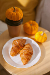 blurred background with seasonal coffee and freshly baked croissants with pumpkins at a cafe