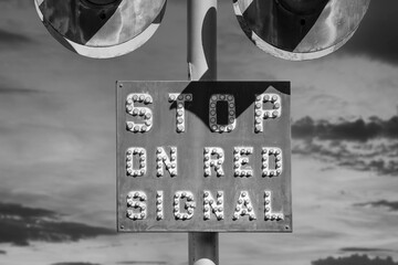 Black and white view of vintage stop on red signal railroad crossing sign.  