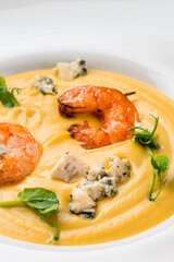 Autumn food pumpkin soup with shrimps. Served for dinner