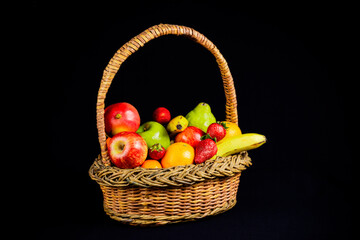 Cesto con frutas frescas, dieta saludable, fondo negro.