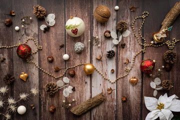 Christmas background with decoration like Christmas bell, balls, pine cones, nuts, chain, on a brown, rustic wooden background in vintage style