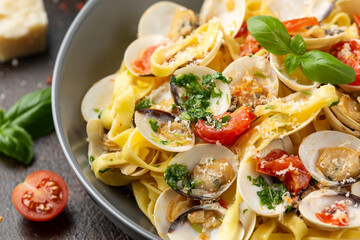 White shell clams in Garlic and parsley white wine sauce tagliatelle pasta served with cherry tomatoes and parmesan cheese