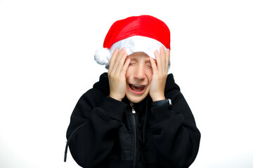 a boy in a red Santa hat holds on and covers his eyes with his hands out of fear