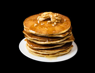 A stack of pancakes with honey and nuts on a black background.