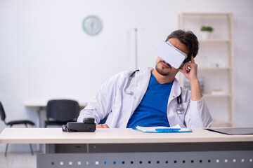 Young male doctor wearing virtual glasses in the clinic