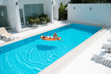 Obraz na płótnie Canvas woman on the mattress swims in the pool