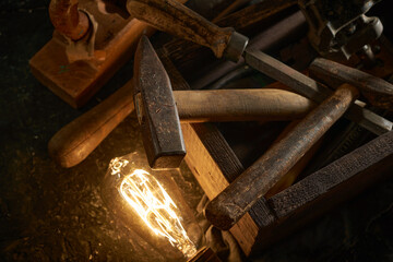 Wooden tool box of used hand tools with old and dirty, rusty wrenches, hammers, and old light bulb