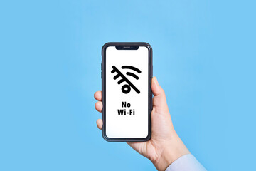 A person holds a mobile phone with No Wi-Fi symbol on screen. Hand holding smartphone with no internet, no connection symbol