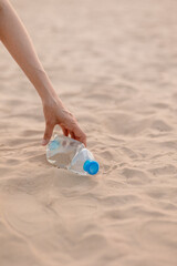 a man collects plastic bottles and garbage on the beach in a public place. eco friendly and caring for nature. collect plastic muslr and take it for recycling. careful attitude to the planet