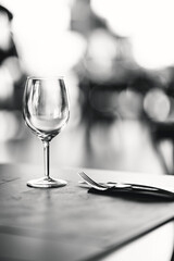 An empty wine glass placed on a table in a fancy restaurant with a knife and a fork next to it